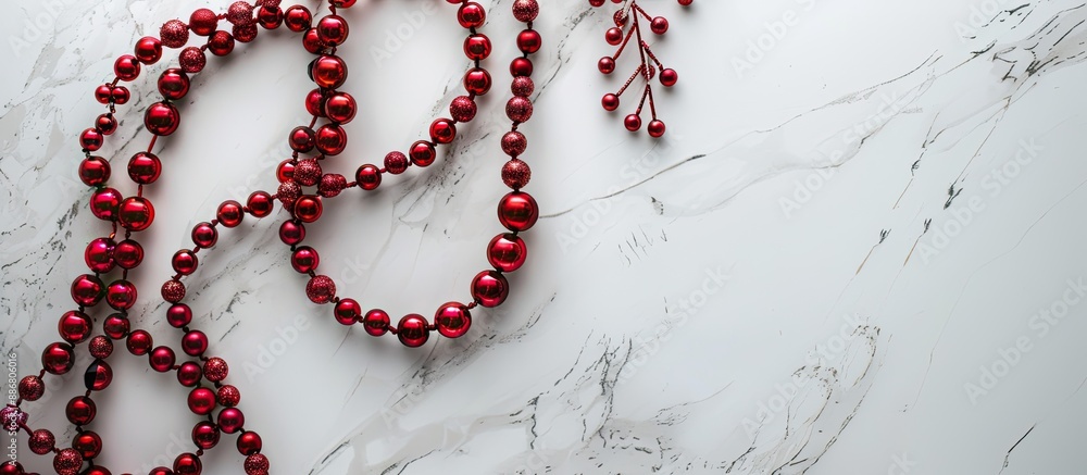 Aufkleber A festive Christmas frame featuring a string of red beads on a sleek marble background, viewed from above with room for text or images.