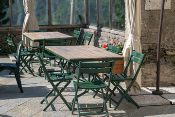 tables and seats in an outdoor restaurant in the square in a tourist location, without people, ready to welcome tourists on holidays, in summer we love to dine outdoors eating typical regional product