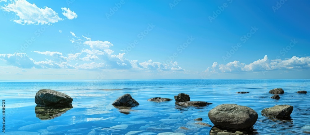Poster a serene copy space image of rocks in the sea under a vast blue sky background.