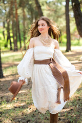 Portrait of beautiful blonde curl girl in medieval dress and fur vest on  nature with horse. Young worker in rural scene in forest.Warm colorful art work.