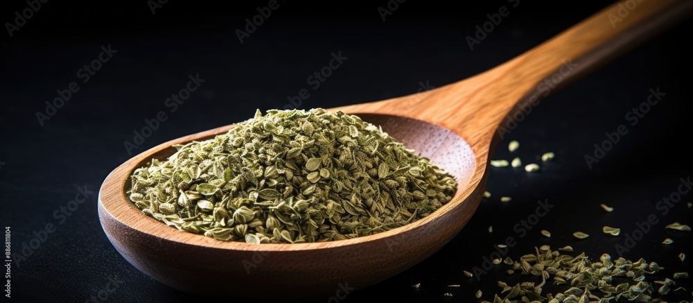 Poster a top-down view of dried oregano herbs in a wooden spoon against a black background with a close-up 