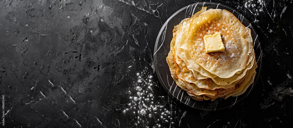 Aufkleber Top view of a stack of crepes with butter on a marble board against a black background, featuring copy space image.