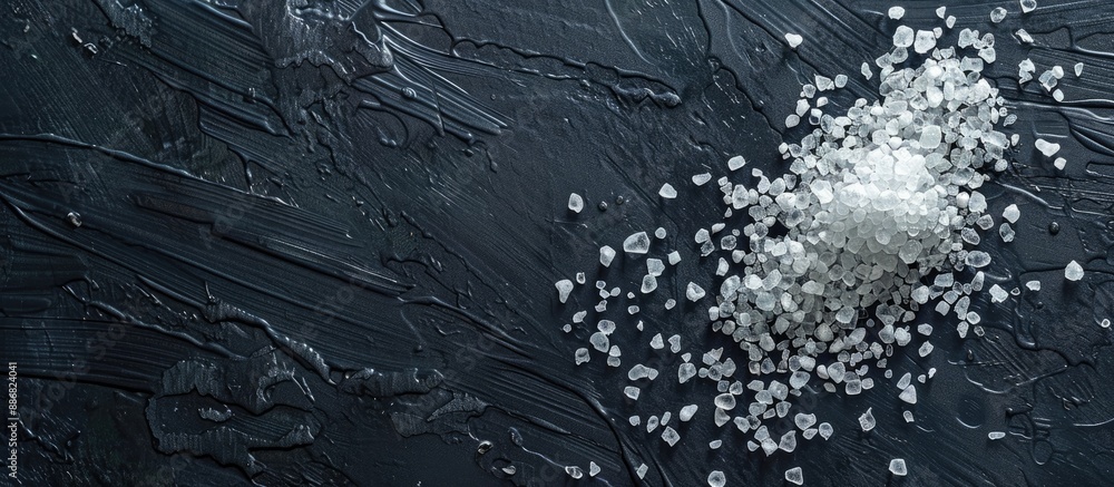 Poster sea salt grains sprinkled on a dark surface with ample copy space image.
