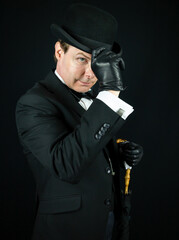 Stylish Businessman in Dark Suit and Leather Gloves Politely Doffing Bowler Hat. Classic English...