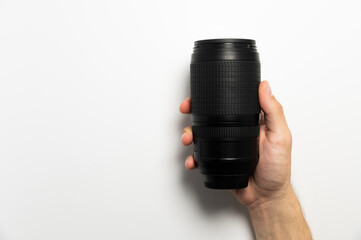 Horizontal shot of a camera lens on the hands of a man holding a zoom telephoto lens