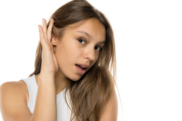Fototapeta premium Young woman over isolated white background listening to something by putting hand on the ear.