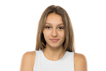 Fototapeta premium Portrait of beautiful young smiling brunette woman without makeup on white studio wall. Pretty female with straight hair in white shirt
