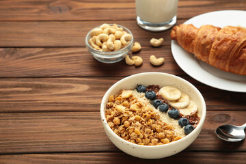Beautiful morning breakfast with fresh croissants and granola with yoghurt on brown wooden background. Tasty and healthy breakfast