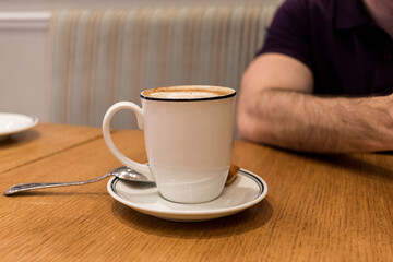 White coffee cup on table in cafe with person on the background