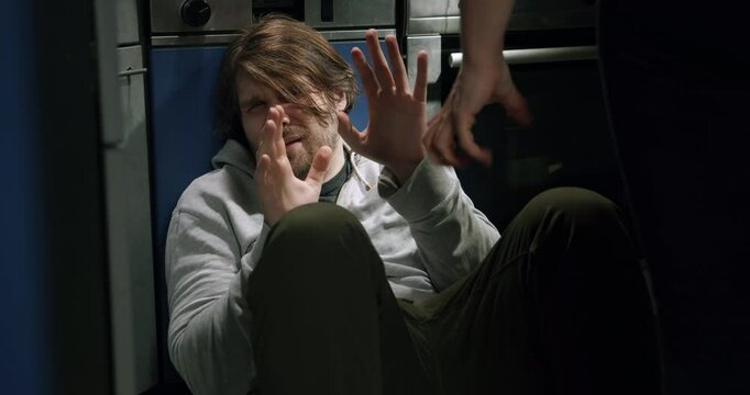 Frightened scared man sitting on the kitchen floor in front of a woman threatening fist hand. Domestic Violence, Domestic Abuse. The problem of male abuse in family relationships 