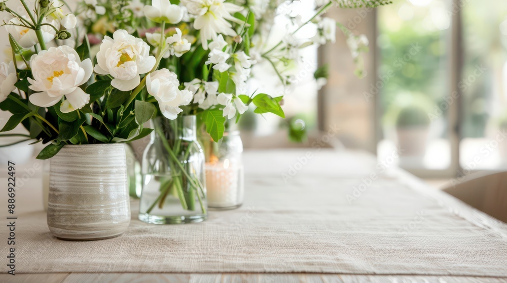 Poster a table with a white tablecloth and three vases of flowers on it