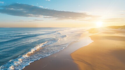 Aerial view of a sandy beach with waves crashing on the shore at sunset.