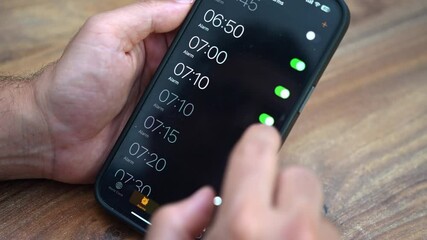 Male CEO of startup company programs smartphone alarm clock ensuring early wake-up to strategize important business plans and lead team effectively for growth