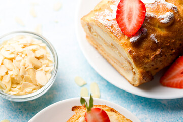 Sliced rolls with custard. The dessert is decorated with fresh strawberries.