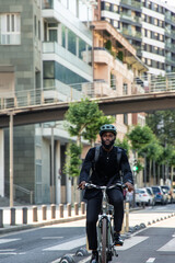 black African businessman with helmet and backpack rides e-bike on city bike lane to work