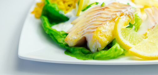 A plate of food with a fish fillet, rice, and lemon slices