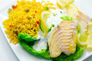 A plate of food with a fish fillet, rice, and lemon slices