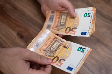 Man financial manager hands hold euro banknotes counting money for earning through currency exchange procedures sitting at wooden desk in company office