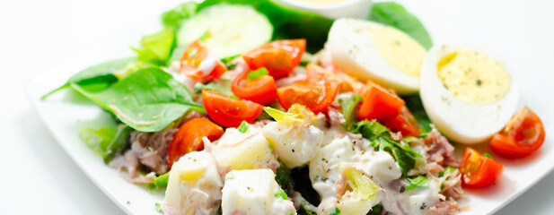 A plate of food with a salad, eggs, and a sauce