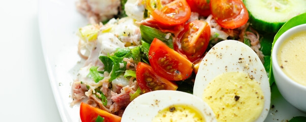 A plate of food with a salad, eggs, and a sauce