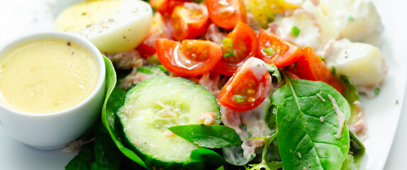 A plate of food with a salad, eggs, and a sauce