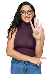 Brunette young woman wearing casual clothes and glasses showing and pointing up with fingers number...