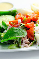 A plate of food with a salad, eggs, and a sauce