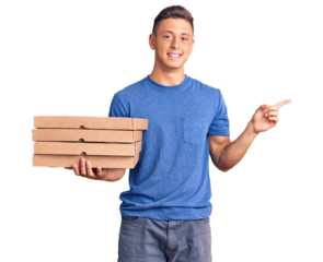 Young handsome hispanic man holding delivery pizza box smiling happy pointing with hand and finger to the side