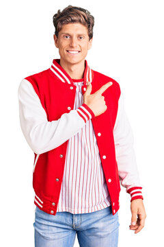 Young handsome man wearing baseball uniform cheerful with a smile on face pointing with hand and finger up to the side with happy and natural expression