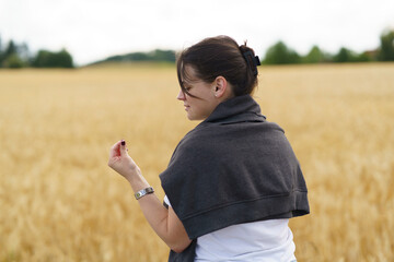 A young smiling beautiful girl with collected hair and a sweater thrown over her shoulders against...