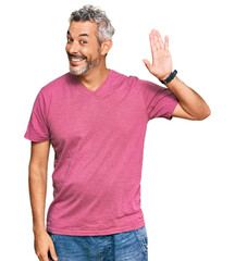 Middle age grey-haired man wearing casual clothes waiving saying hello happy and smiling, friendly...