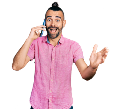 Hispanic man with ponytail having conversation talking on the smartphone celebrating victory with happy smile and winner expression with raised hands