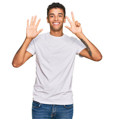 Young handsome african american man wearing casual white tshirt showing and pointing up with fingers number eight while smiling confident and happy.
