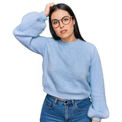 Young hispanic woman wearing casual clothes and glasses confuse and wonder about question....