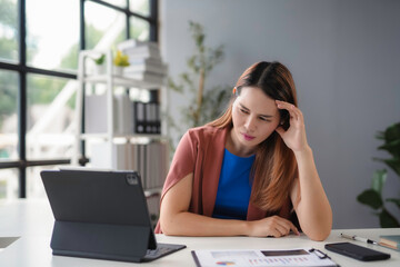 Businesswoman is experiencing stress and headache while working on a laptop computer, highlighting the pressures of a demanding job