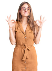 Young beautiful blonde woman wearing casual clothes and glasses relaxed and smiling with eyes closed doing meditation gesture with fingers. yoga concept.