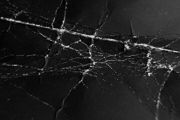 Black wrinkled crinkled worn rough paper surface with white cracks and old grunge scuffs. Abstract dark cardboard background