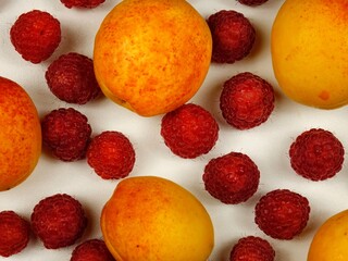 Ripe apricots and raspberries lie on a white background, top view