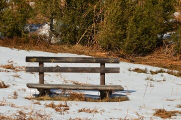 wooden bench on the slope in winter in the snow