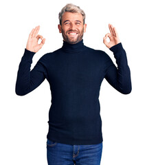 Young handsome blond man wearing casual turtleneck sweater relax and smiling with eyes closed doing meditation gesture with fingers. yoga concept.