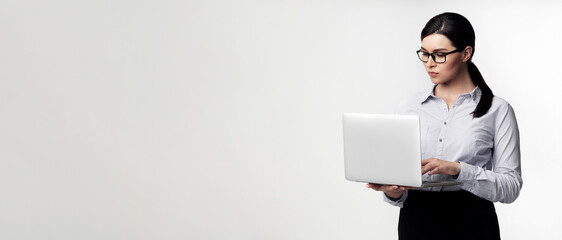 A woman in a gray shirt and black skirt uses a laptop computer in a studio.