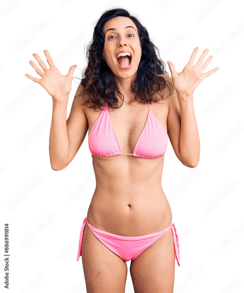 Wall mural young beautiful hispanic woman wearing bikini celebrating crazy and amazed for success with arms rai