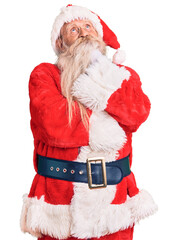 Old senior man with grey hair and long beard wearing traditional santa claus costume with hand on...
