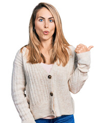 Young blonde woman wearing casual clothes surprised pointing with hand finger to the side, open mouth amazed expression.