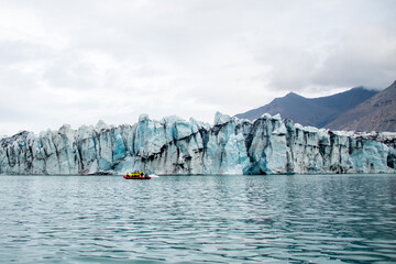 A boat next to a glacier cliff in jokulsarlon in Iceland
