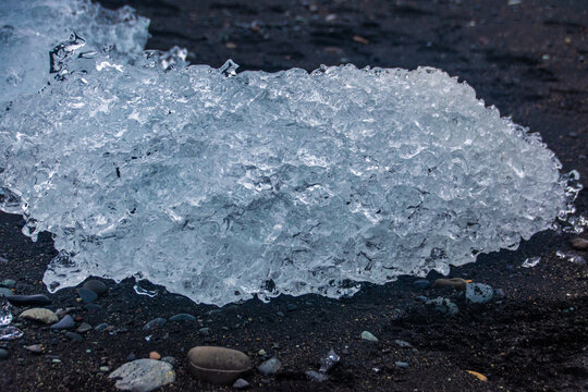 stranded icebergs on a dark pebbly beach in j&ouml;kuls&aacute;rl&oacute;n in iceland