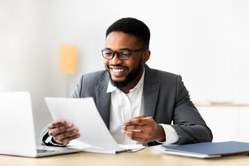 Cheerful african american businessman checking reports and making notes, copy space