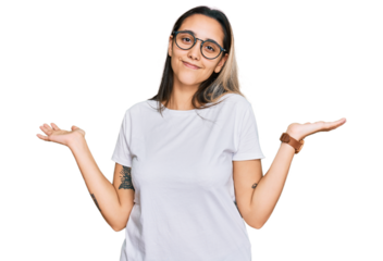 Young hispanic woman wearing casual white t shirt clueless and confused expression with arms and hands raised. doubt concept.