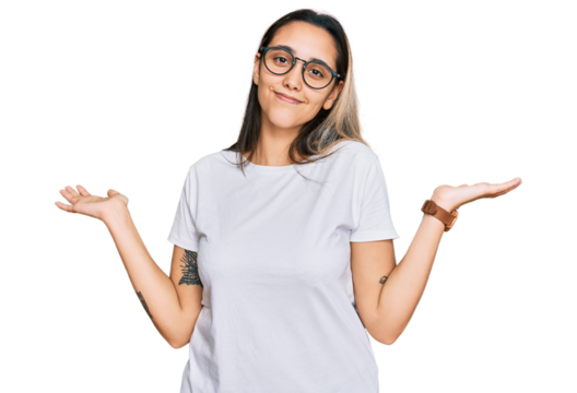 Young hispanic woman wearing casual white t shirt clueless and confused expression with arms and hands raised. doubt concept.