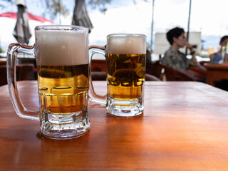 Jars of beer on a table in an outdoor restaurant.